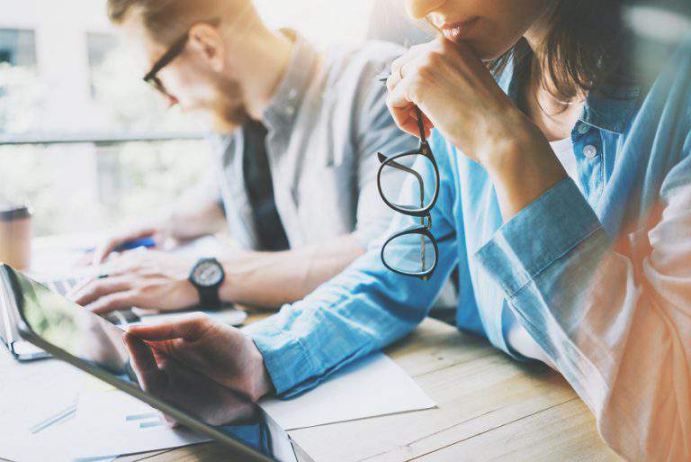 Coworking team brainstorming in modern office.Project Manager Researching Process,holding Glasses Female Hand.Young Business Crew Working with Startup Studio.Using Digital Tablet.Blurred,film effect