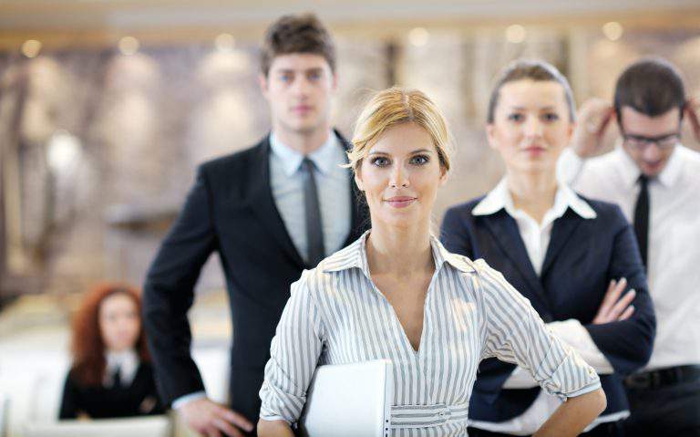 13276442 - business woman standing with her staff in background at modern bright office conference room
