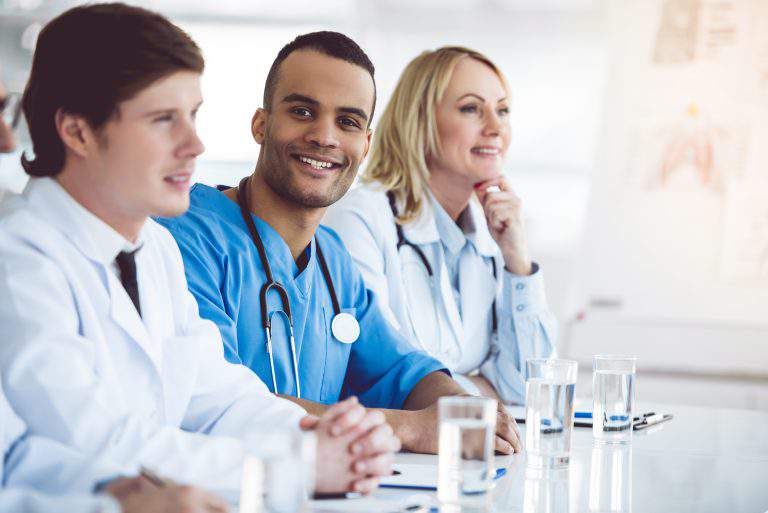 Successful medical doctors are smiling while sitting at the conference
