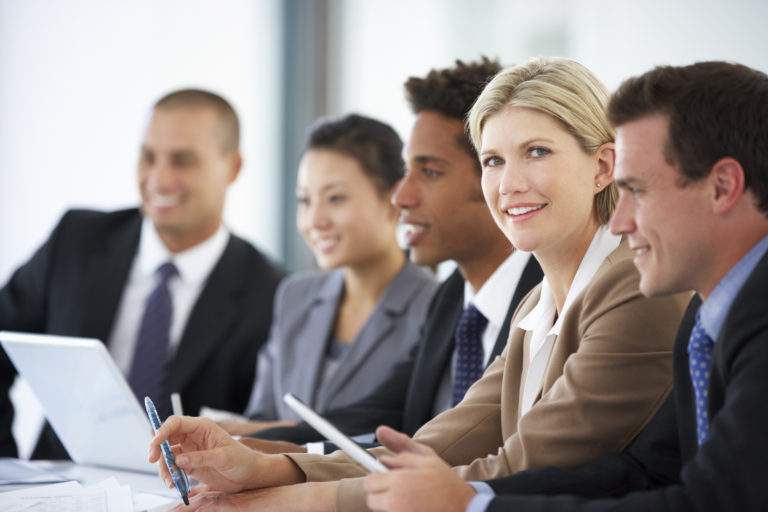Portrait Of Female Executive Attending Office Meeting With Colleagues