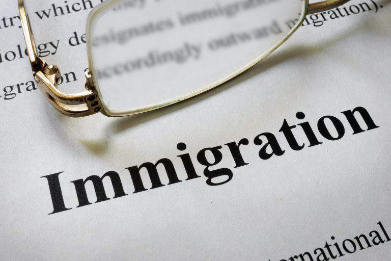 Paper with word immigration and glasses. Law concept.